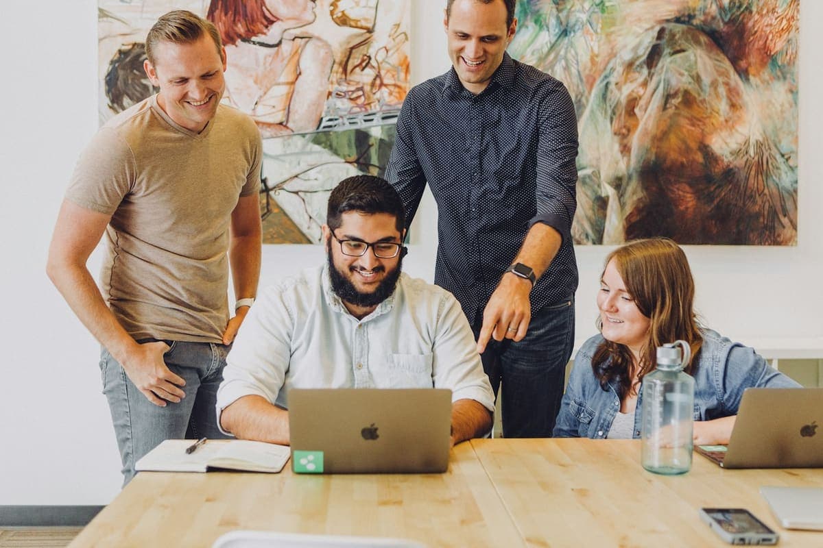 Smiling team gathered around a laptop