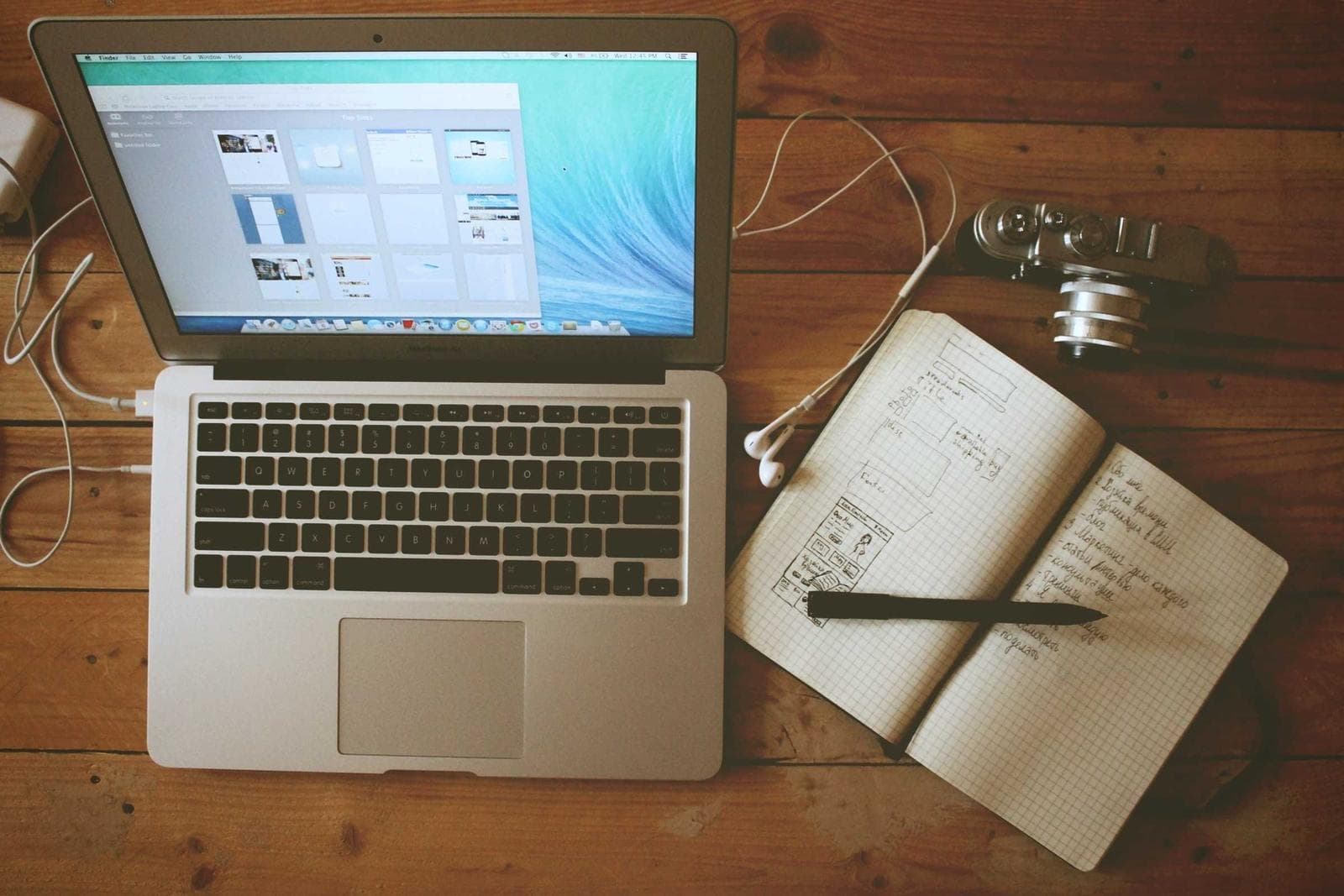 Laptop beside an open notebook with handwritten plans